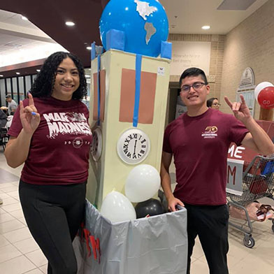 TAMIU student next to spirit week cart