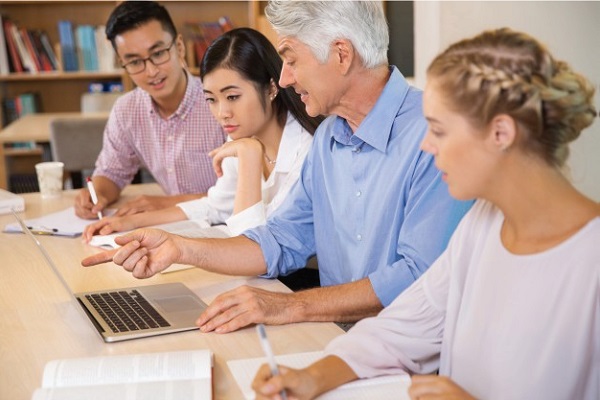 Example of a faculty member speaking with students, while pointing to something on his laptop.