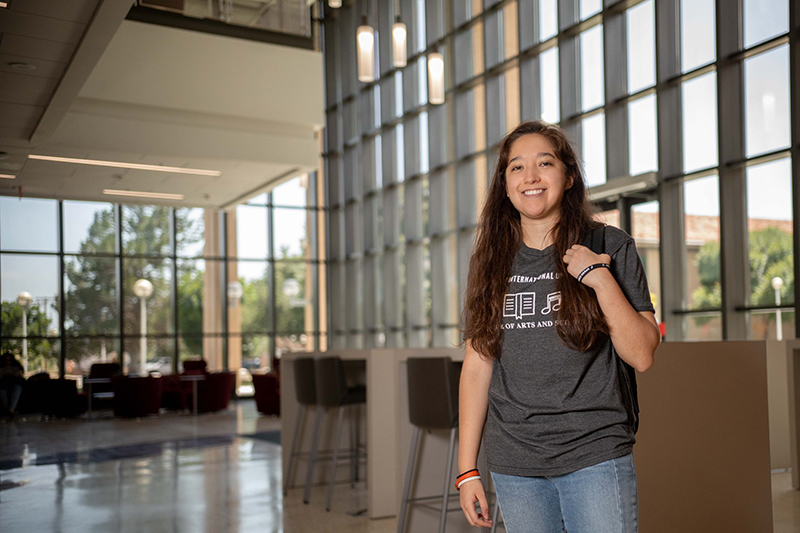 Student standing with a backpack inside the Academic Innovation Center