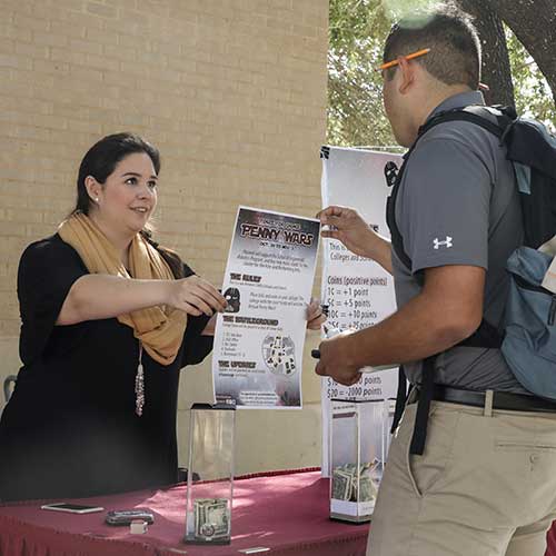 Woman showing a male student a map showing Penny Wars donation sites.