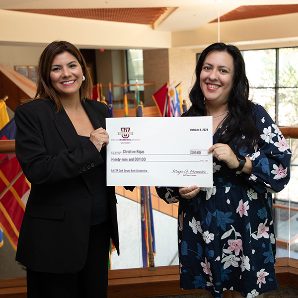 Christine Rojas given a check by Staff Senate President Mayra Hernandez